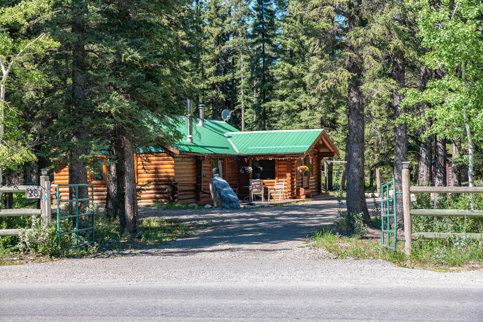 A log building with a green roof set in pine forest in Bragg Creek