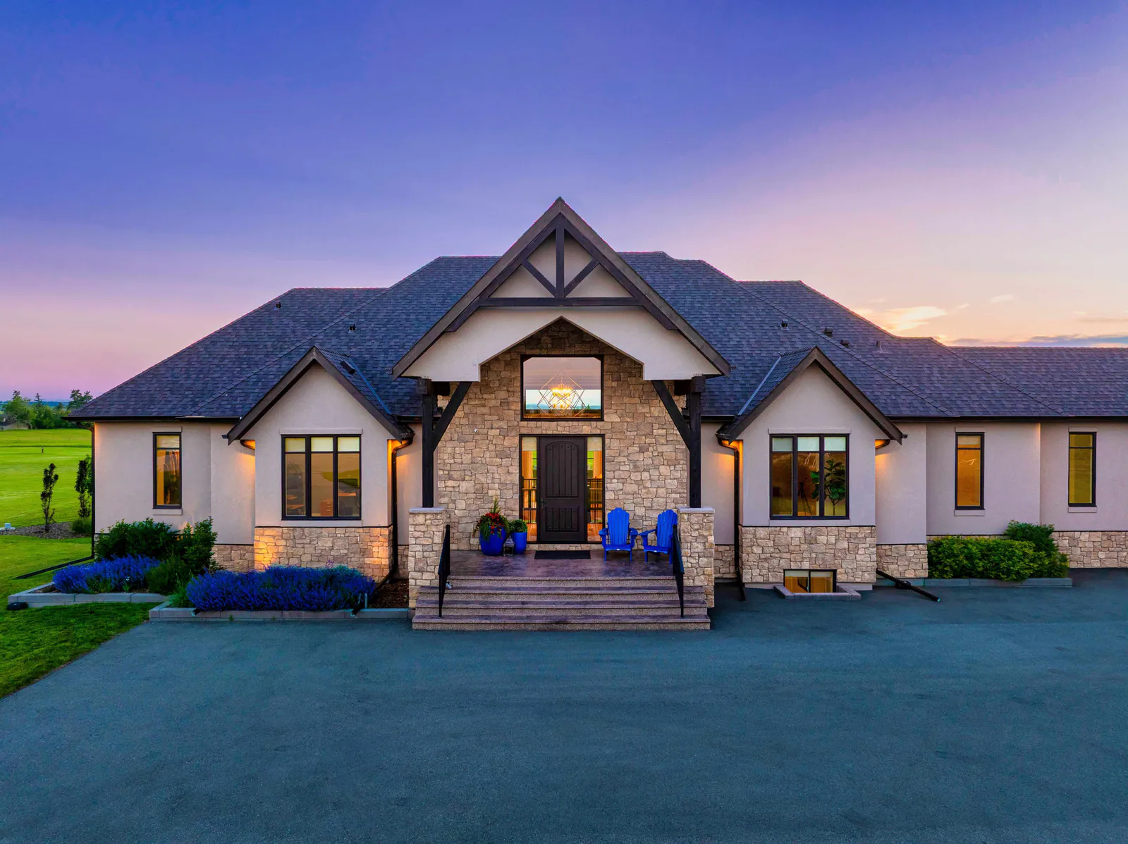 Front elevation at twilight with timber-frame gable entry and stone