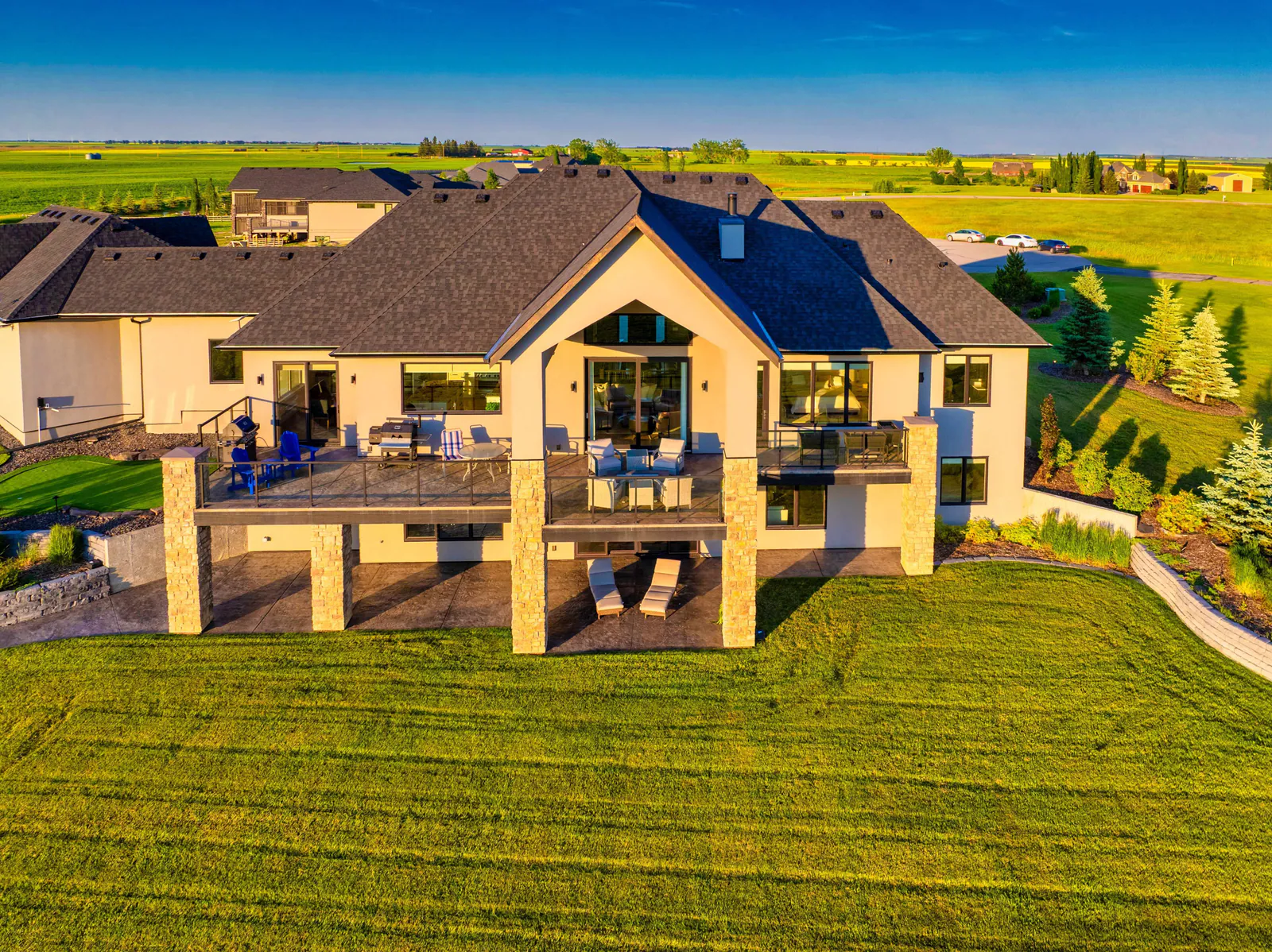 Low aerial of the rear balcony, walkout patio and landscaping